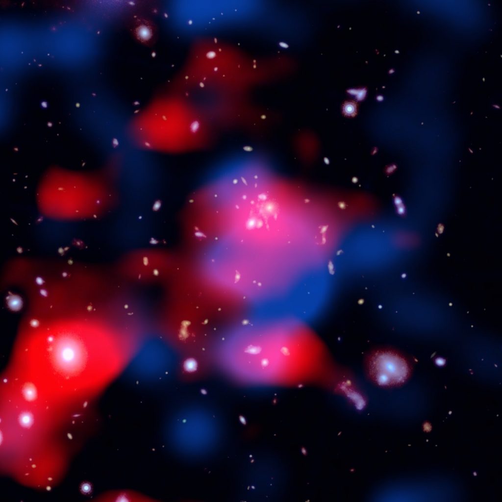This stunning image reveals a distant galaxy cluster teeming with energy: galaxies shine in visible light (white), ghostly red clouds unveil a newly discovered radio mini-halo—the most distant ever detected—and blue wisps trace the hot gas glowing in X-rays. Credit: Chandra X-ray Center (X-ray: NASA/CXC/SAO; Optical: NASA/ESA/STScI; Radio: ASTRON/LOFAR; Image Processing: NASA/CXC/SAO/N. Wolk)